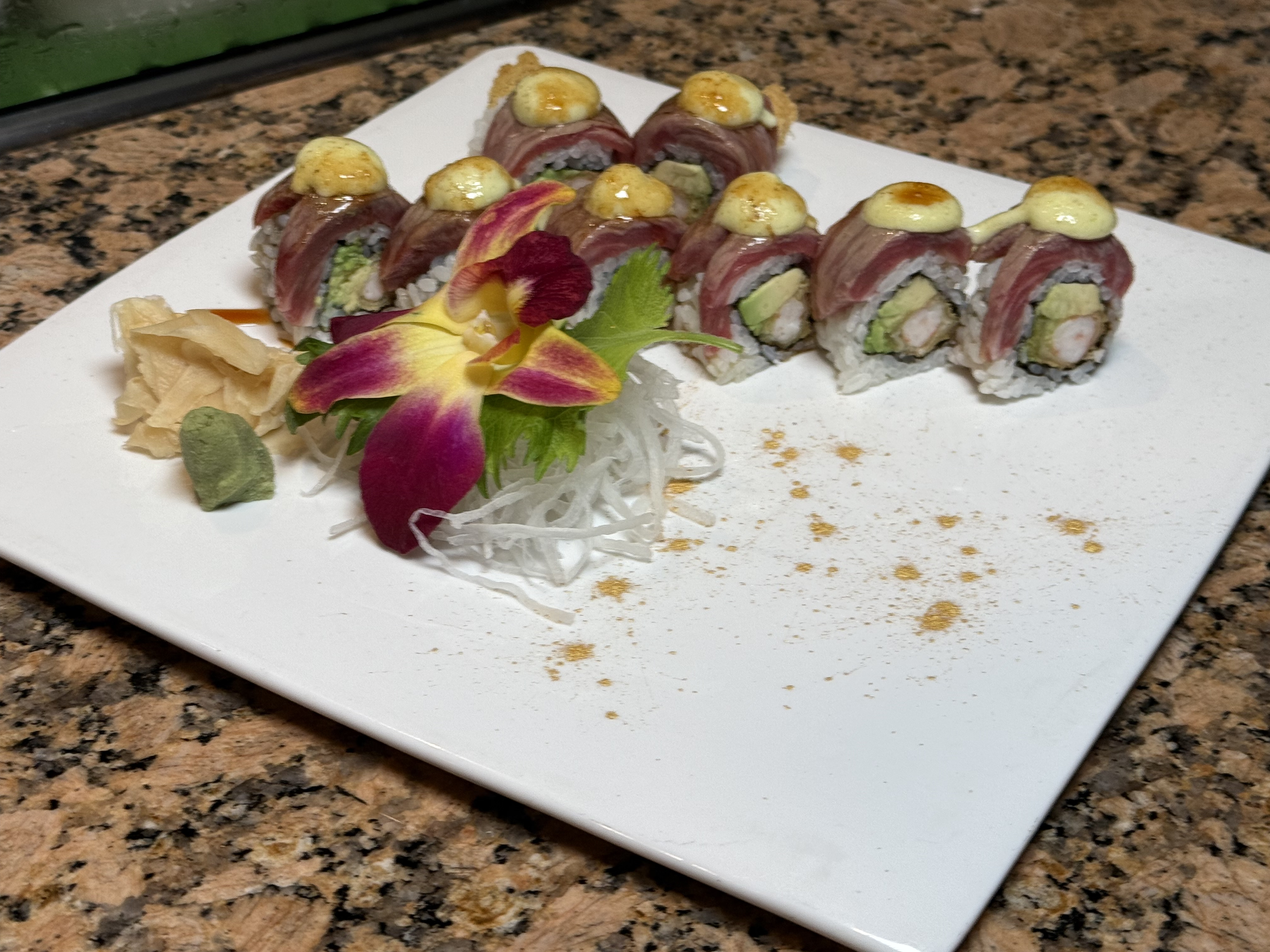 Tuna topped sushi roll with orchid garnish